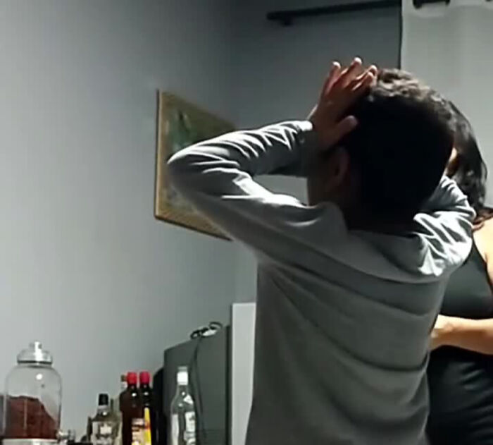 Man in a gray shirt reacting to a prank in a kitchen, surrounded by various bottles on the counter. Man in a gray shirt reacting to a prank in a kitchen, surrounded by various bottles on the counter.