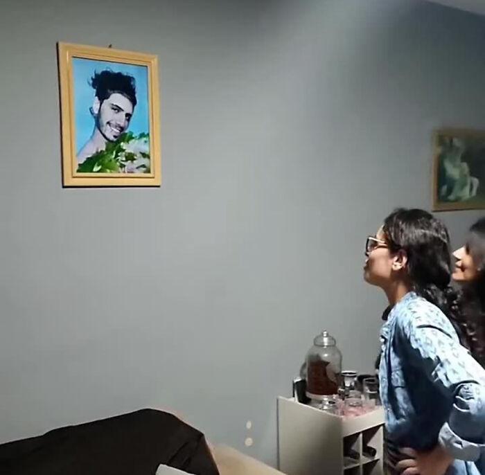 Two women laughing at a framed prank photo on the wall. Two women laughing at a framed prank photo on the wall.