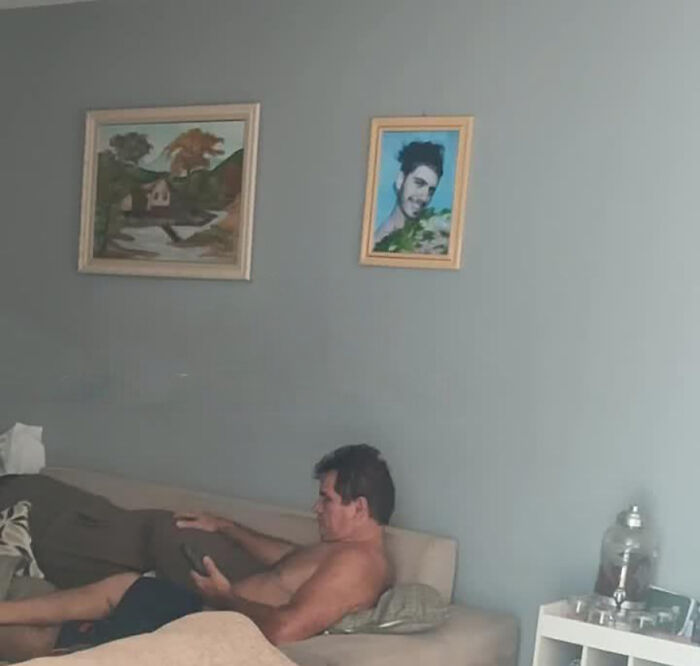 Man sitting on a couch, surrounded by art, involved in a funny prank on his family. Man sitting on a couch, surrounded by art, involved in a funny prank on his family.