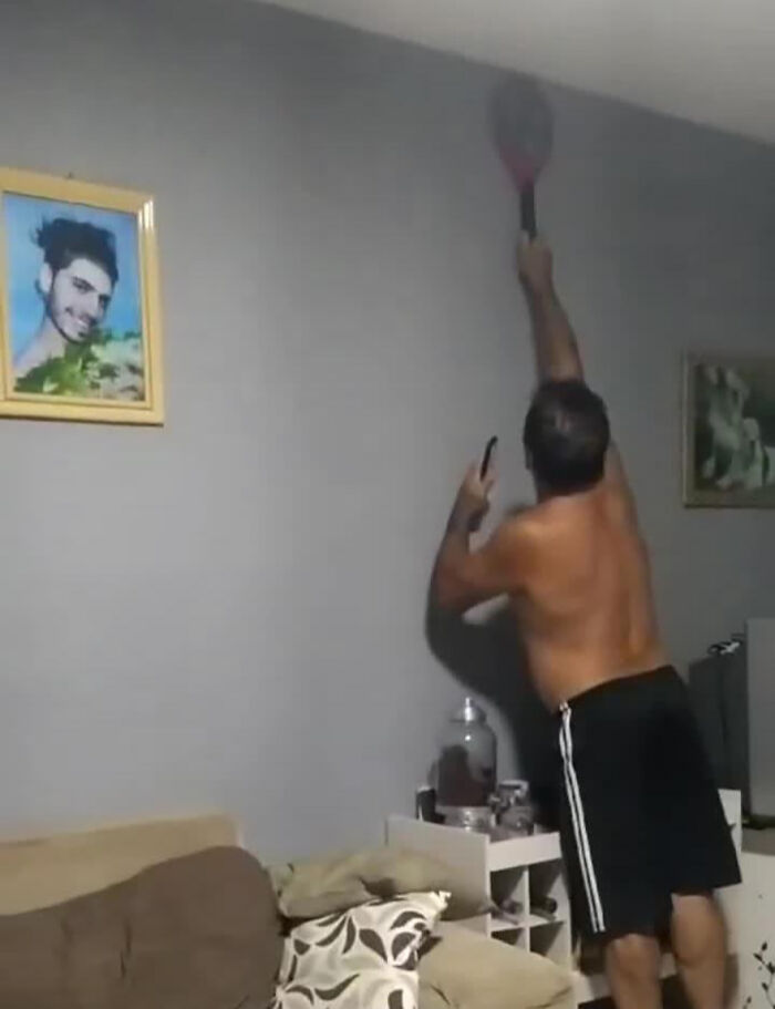 A man pranking his family, reaching with a tennis racket in a living room, captured in a humorous moment. A man pranking his family, reaching with a tennis racket in a living room, captured in a humorous moment.