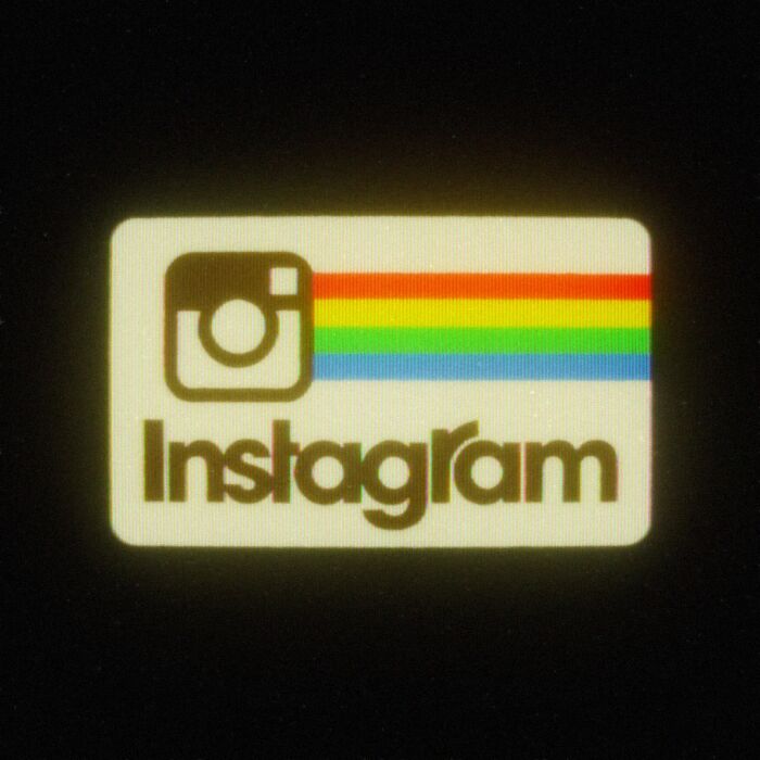 Retro 80s twist on Instagram's modern logo with rainbow stripes on a dark background.