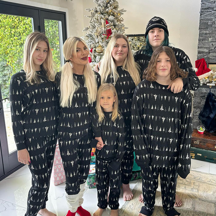 Family wearing matching pajamas in front of Christmas tree. Family wearing matching pajamas in front of Christmas tree.