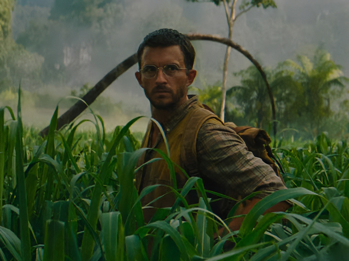Jonathan Bailey with glasses and a backpack in a jungle setting. Jonathan Bailey with glasses and a backpack in a jungle setting.