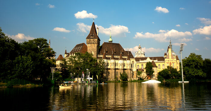 Historic and beautiful building by a serene lake under a blue sky.