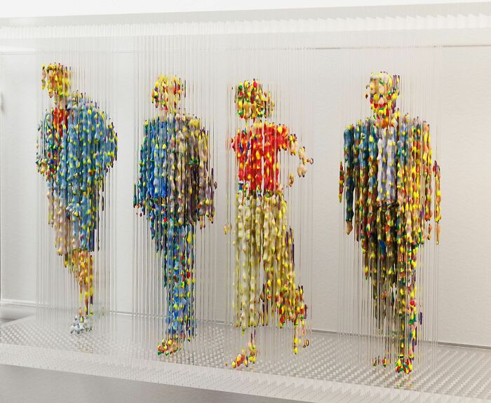 Three-dimensional, fragmented paintings of people with colorful pixelated design suspended on strings.