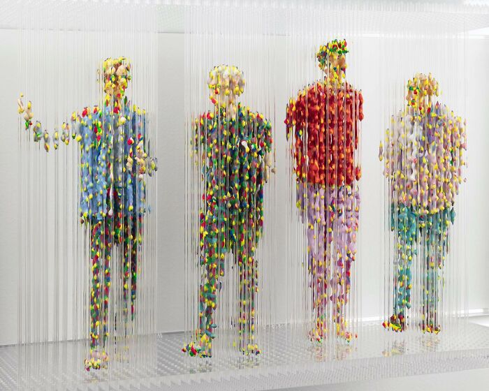 Three-dimensional, fragmented paintings of four people by Chris Dorosz, composed of colorful suspended dots.