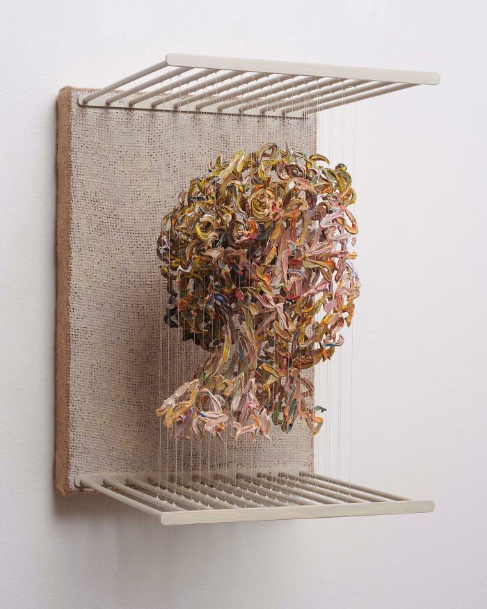 Three-dimensional painting of a head, featuring vibrant colors on suspended paint strips, illustrating a fragmented form.
