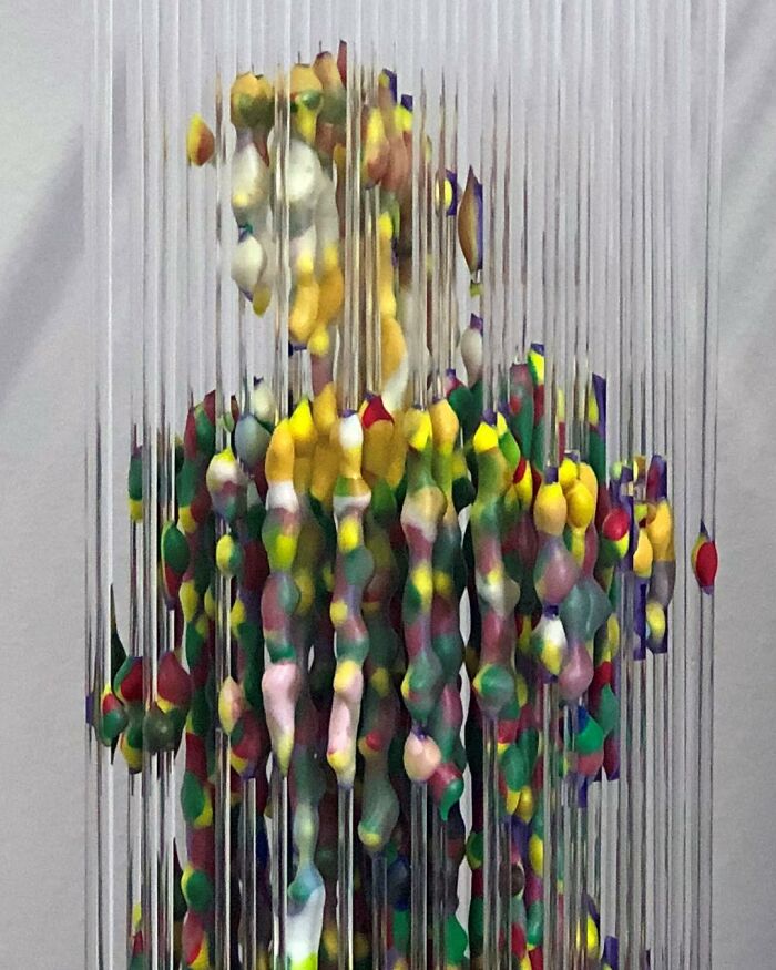 Three-dimensional painting of a person by Chris Dorosz, showing colorful fragmented forms across vertical rods.