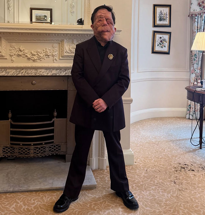 Person in a formal suit stands confidently by a fireplace, showcasing resilience against "anti-trans" claims. Person in a formal suit stands confidently by a fireplace, showcasing resilience against "anti-trans" claims.