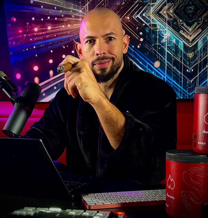 Man in a black robe holding a cigar, with a laptop and microphone, against a colorful abstract background. Man in a black robe holding a cigar, with a laptop and microphone, against a colorful abstract background.