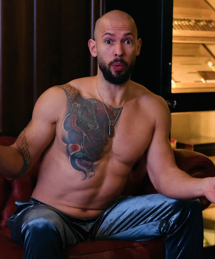 Shirtless man with tattoos sitting on a leather sofa, gesturing expressively. Shirtless man with tattoos sitting on a leather sofa, gesturing expressively.
