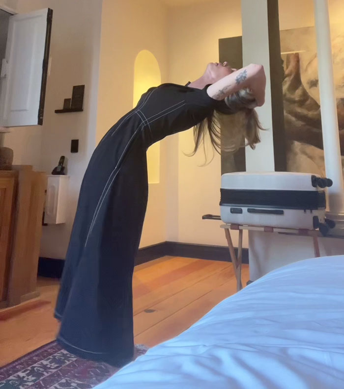 Woman stretching indoors, expressing frustration about rain showers being anti-women. Woman stretching indoors, expressing frustration about rain showers being anti-women.