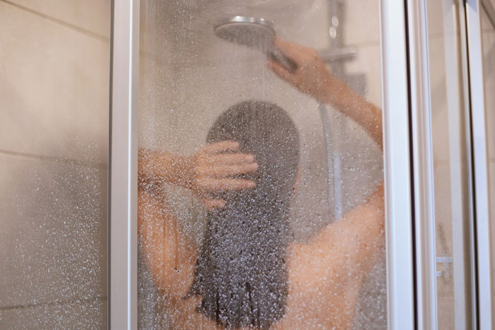 Woman showering, with water drops on glass, discussing rain showers as anti-women. Woman showering, with water drops on glass, discussing rain showers as anti-women.