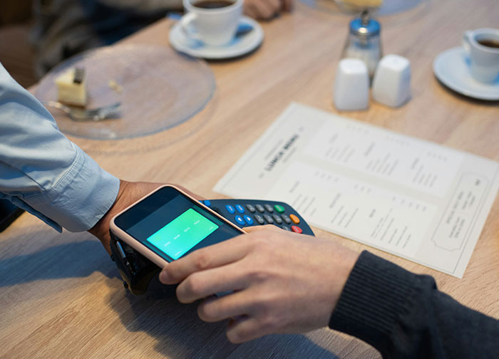 Customer using a phone to pay at a restaurant, sparking a debate on tipping practices. Customer using a phone to pay at a restaurant, sparking a debate on tipping practices.