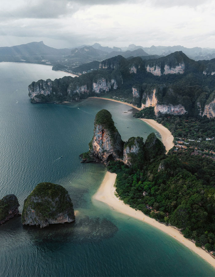 Aerial view of scenic beach and cliffs in Thailand, surrounded by turquoise waters. Aerial view of scenic beach and cliffs in Thailand, surrounded by turquoise waters.
