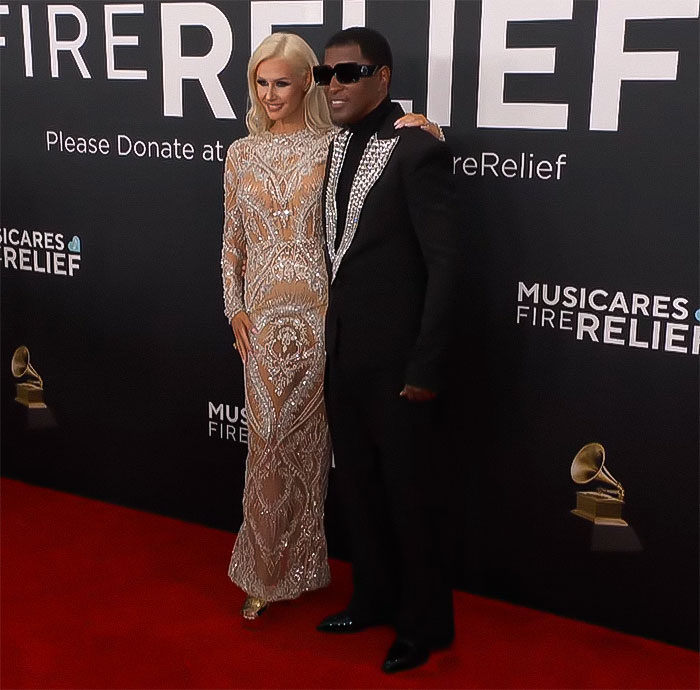 Couple on the red carpet at MusiCares event, standing against a Fire Relief backdrop. Couple on the red carpet at MusiCares event, standing against a Fire Relief backdrop.