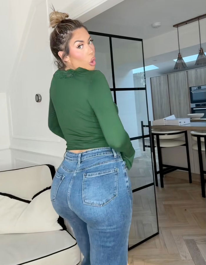 Woman in green top and jeans flaunts new figure after BBL removal in a stylish, modern kitchen setting. Woman in green top and jeans flaunts new figure after BBL removal in a stylish, modern kitchen setting.
