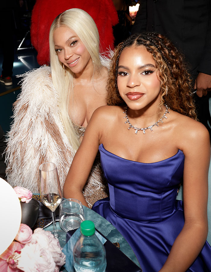 Two individuals seated at an event, one in a blue dress, showcasing striking resemblance to each other. Two individuals seated at an event, one in a blue dress, showcasing striking resemblance to each other.