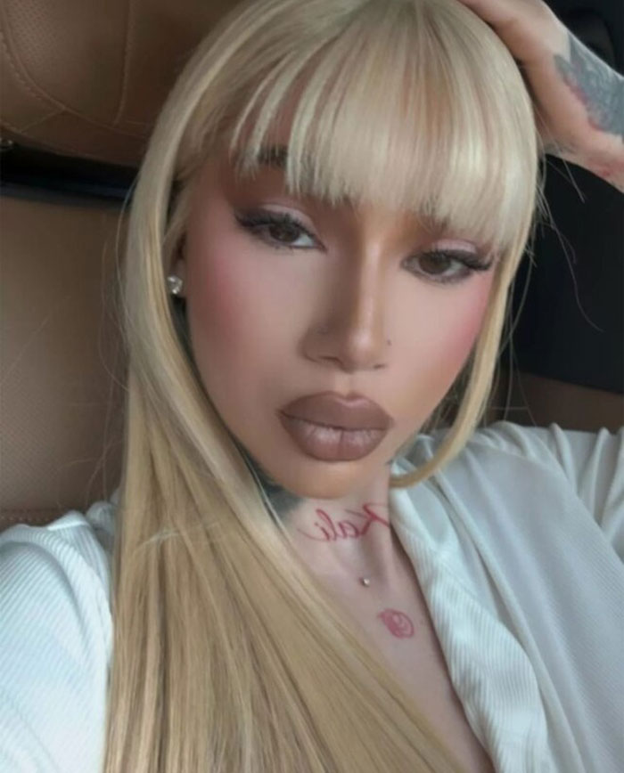 Blonde woman with a straight hairstyle, wearing a white top, looking directly at the camera in a car. Blonde woman with a straight hairstyle, wearing a white top, looking directly at the camera in a car.