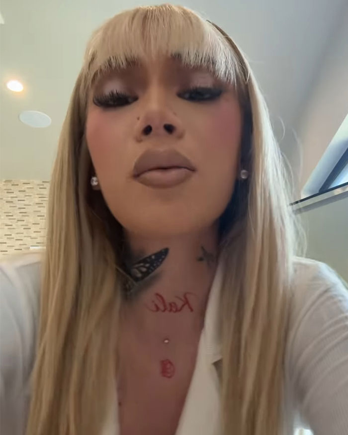 Blonde woman with bangs and tattoos, wearing earrings and a white top, related to "47-Year-Old Mob Wife" controversy. Blonde woman with bangs and tattoos, wearing earrings and a white top, related to "47-Year-Old Mob Wife" controversy.