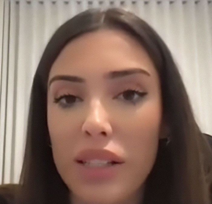 A woman with long hair and makeup, highlighting plastic surgery changes, in front of a curtain backdrop. A woman with long hair and makeup, highlighting plastic surgery changes, in front of a curtain backdrop.