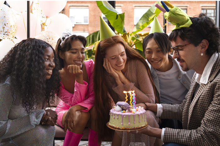 Friends celebrating a lady's birthday with cake, wearing party hats and smiling. Friends celebrating a lady's birthday with cake, wearing party hats and smiling.