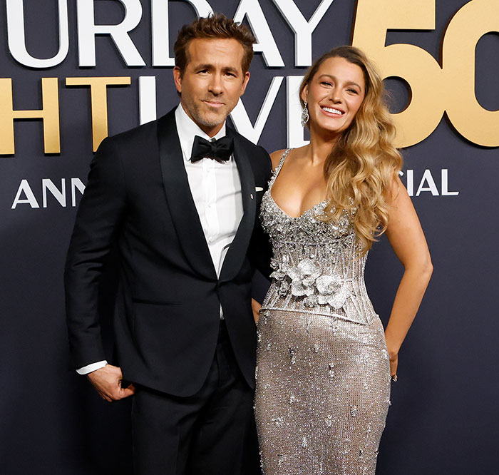 Blake Lively and Ryan Reynolds in elegant attire at SNL 50 event backdrop. Blake Lively and Ryan Reynolds in elegant attire at SNL 50 event backdrop.