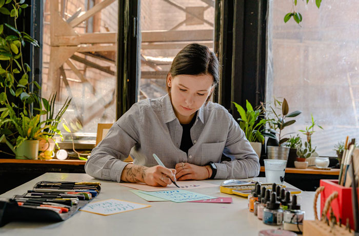 Woman writing at a desk, surrounded by plants, illustrating a story about a bridezilla seeking refunds. Woman writing at a desk, surrounded by plants, illustrating a story about a bridezilla seeking refunds.