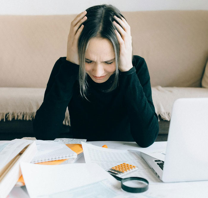 Stressed woman with hands on head at desk, surrounded by paperwork, seeking refunds after wedding didn't work out. Stressed woman with hands on head at desk, surrounded by paperwork, seeking refunds after wedding didn't work out.