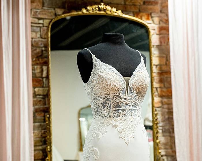 Wedding dress with lace details on a mannequin in front of a mirror, highlighting bridal fashion choices. Wedding dress with lace details on a mannequin in front of a mirror, highlighting bridal fashion choices.