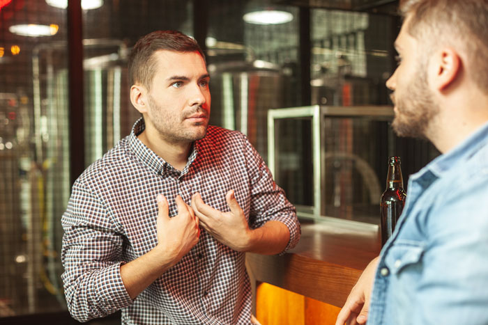 Man at a bar looking frustrated while talking to another, upset about being a bad pet parent. Man at a bar looking frustrated while talking to another, upset about being a bad pet parent.