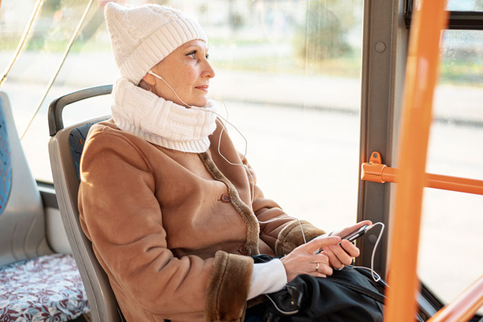 Woman on bus wearing winter clothing, sitting calmly despite plenty of free seats available. Woman on bus wearing winter clothing, sitting calmly despite plenty of free seats available.
