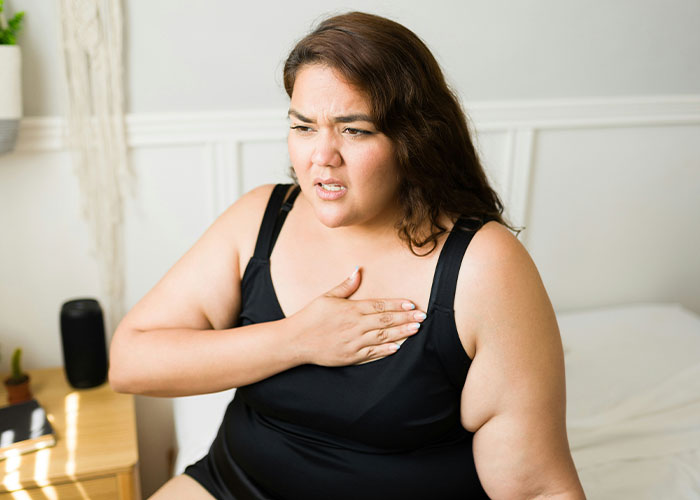 Woman expressing concern, touching her chest, representing health and weight conflict. Woman expressing concern, touching her chest, representing health and weight conflict.