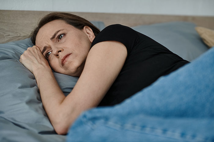 Woman lying in bed, looking upset after canceling a dinner due to no one showing up. Woman lying in bed, looking upset after canceling a dinner due to no one showing up.