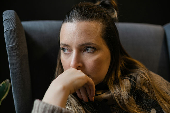 Thoughtful woman in a chair, reflecting on a canceled birthday dinner. Thoughtful woman in a chair, reflecting on a canceled birthday dinner.