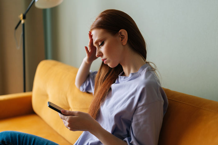 Woman upset after boyfriend cancels date, sitting on sofa and looking at phone. Woman upset after boyfriend cancels date, sitting on sofa and looking at phone.