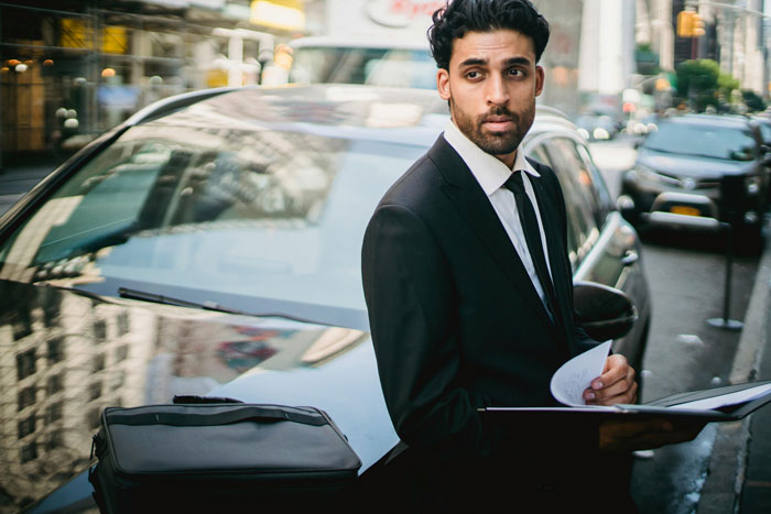 A professional man in a suit stands by a car on a city street, representing professions with more cheaters. A professional man in a suit stands by a car on a city street, representing professions with more cheaters.