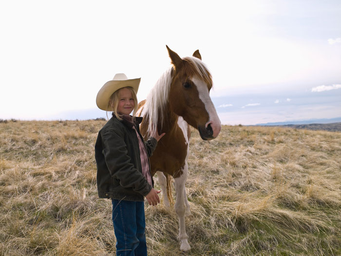 Child in cowboy hat with horse in open field. Child in cowboy hat with horse in open field.