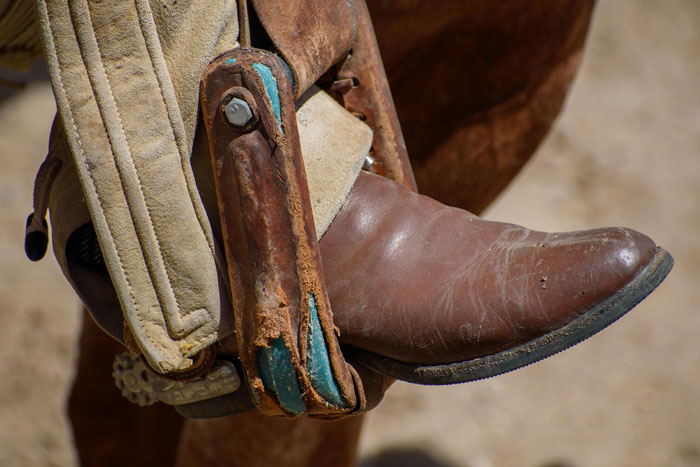 A brown cowboy boot in a stirrup, highlighting the unique function of cowboy boots on fences. A brown cowboy boot in a stirrup, highlighting the unique function of cowboy boots on fences.