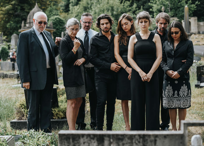Group of people in formal attire mourning at a cemetery. Group of people in formal attire mourning at a cemetery.