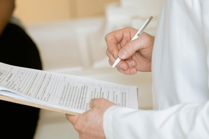 Person holding a pen and clipboard, possibly filing an HR complaint related to a coworker situation. Person holding a pen and clipboard, possibly filing an HR complaint related to a coworker situation.