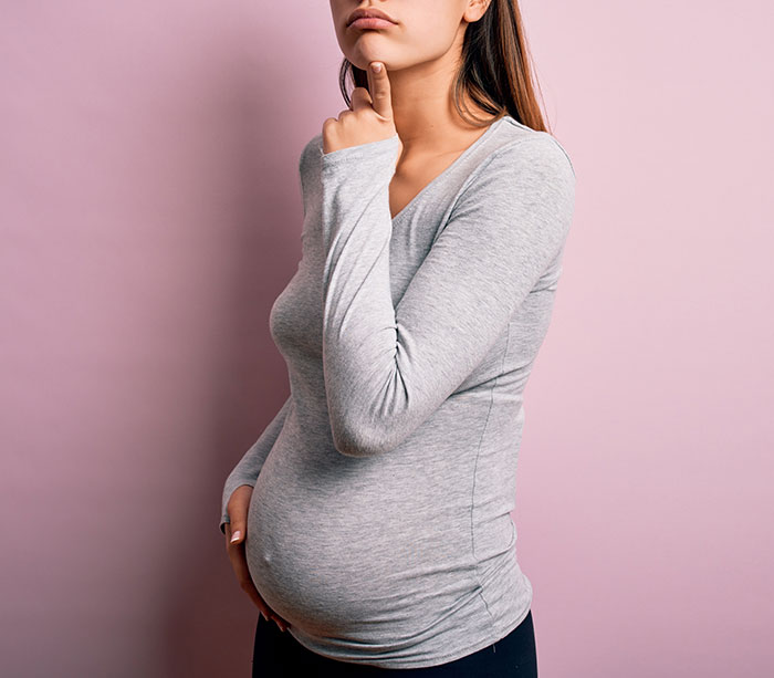 Pregnant teen in gray shirt pondering, highlighting medical mystery case. Pregnant teen in gray shirt pondering, highlighting medical mystery case.