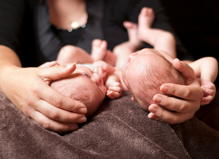 A mother cradling newborn twins, highlighting family dynamics and parenting challenges. A mother cradling newborn twins, highlighting family dynamics and parenting challenges.