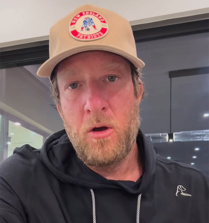 Man in New England Patriots cap and black hoodie discussing controversial Grammys dress. Man in New England Patriots cap and black hoodie discussing controversial Grammys dress.