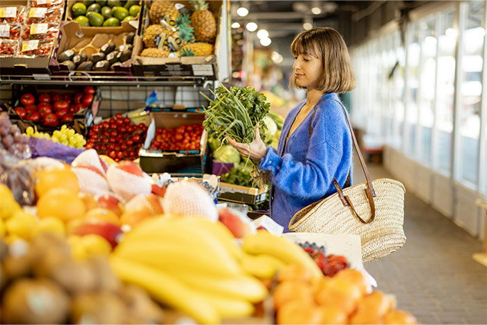 Woman selecting fresh greens in a vibrant grocery store produce section. Woman selecting fresh greens in a vibrant grocery store produce section.