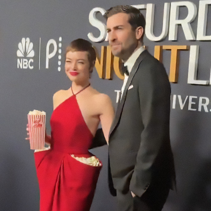 Red carpet appearance with Emma Stone in a popcorn dress at SNL event. Red carpet appearance with Emma Stone in a popcorn dress at SNL event.