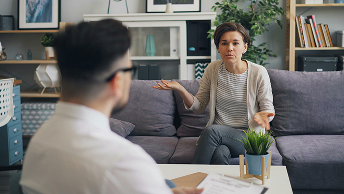 Woman discussing untrainable dog issues with man in living room setting. Woman discussing untrainable dog issues with man in living room setting.