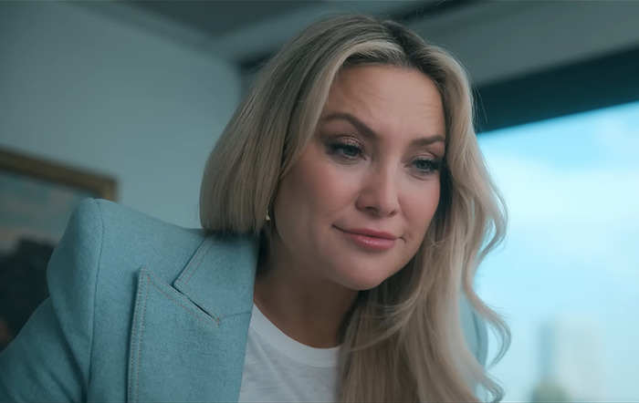 Kate Hudson in a blue blazer looking down with a thoughtful expression, indoors. Kate Hudson in a blue blazer looking down with a thoughtful expression, indoors.