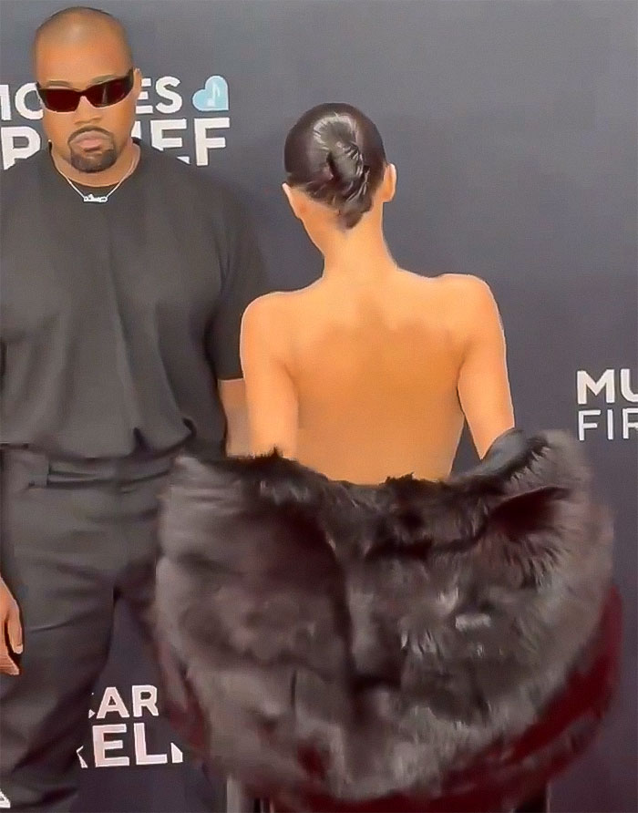 Person in elegant fur outfit, standing beside another in black, showcasing classy fashion style at an event. Person in elegant fur outfit, standing beside another in black, showcasing classy fashion style at an event.