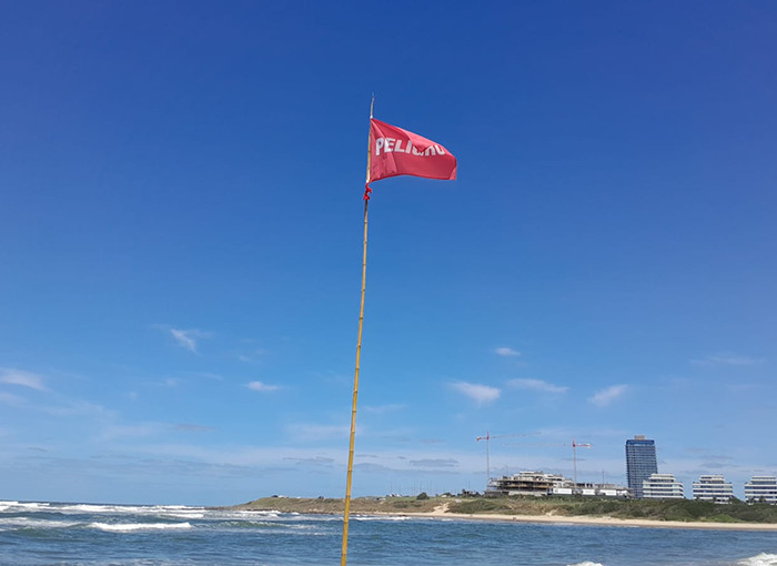 Red warning flag on a beach, indicating caution for lifeguards and swimmers in a coastal setting. Red warning flag on a beach, indicating caution for lifeguards and swimmers in a coastal setting.